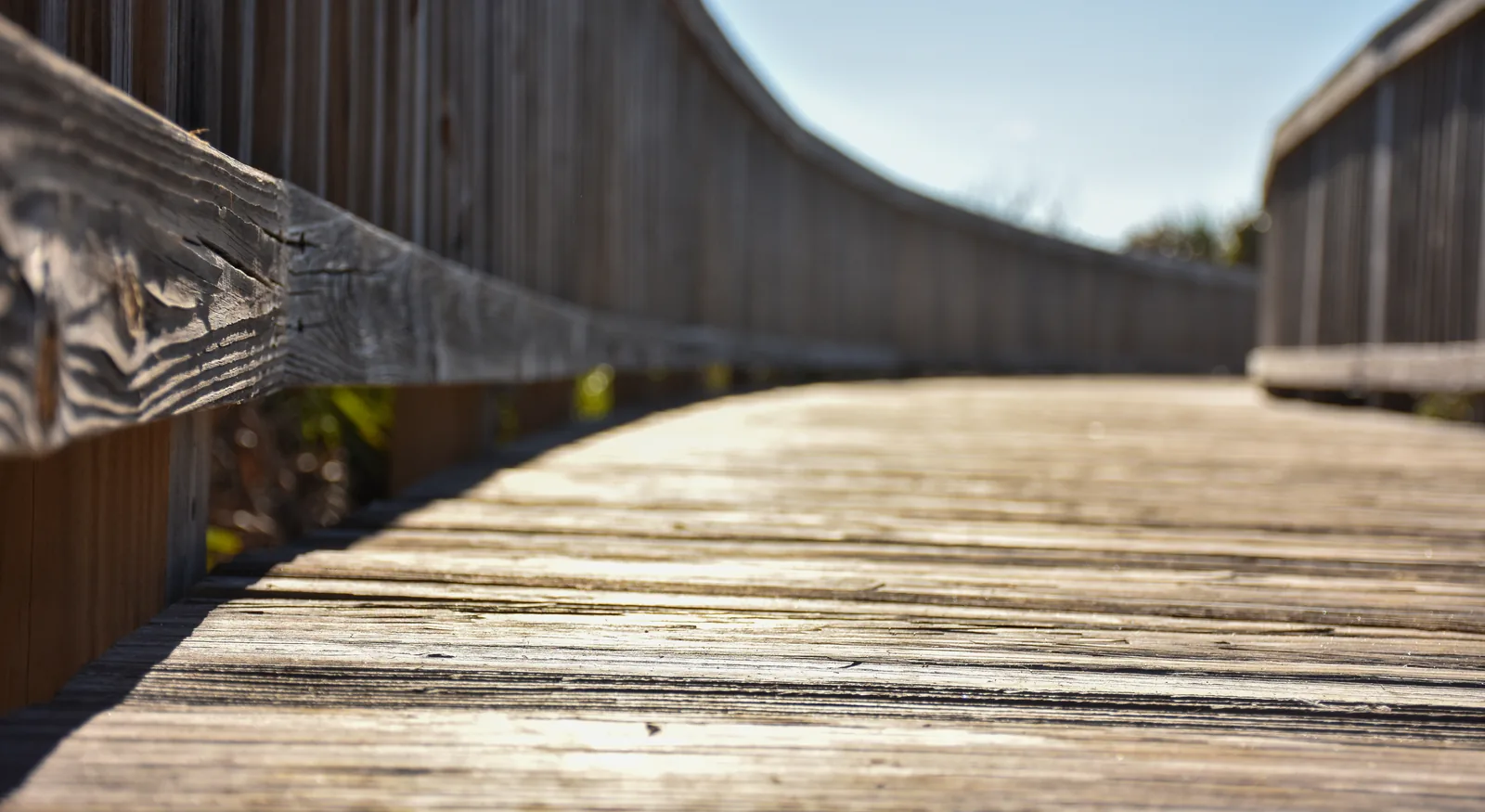 Wood deck boards running away from the camera beside a curved rail