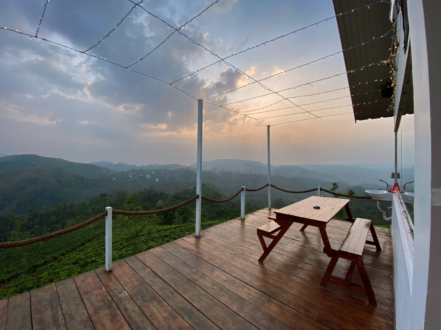 Deck with a picnic table and a rope rail above a valley at dusk