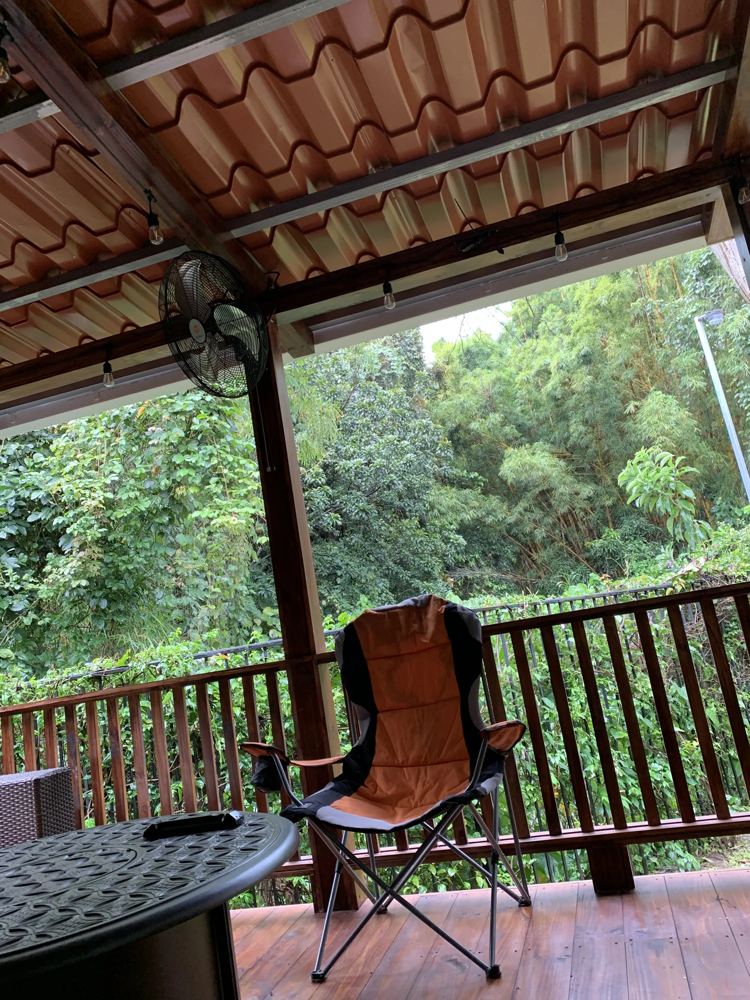 Covered porch with a tiled roof, a wood railing and a chair